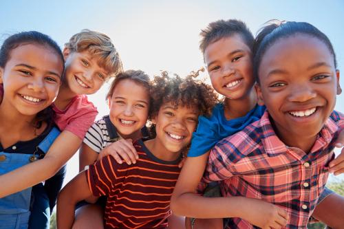 A group of kids outside, goofing off and smiling at the camera