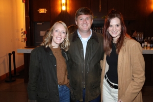 Photo of Michelle and Ted Moore and Brooke Chhina, standing and smiling at camera in a bar setting