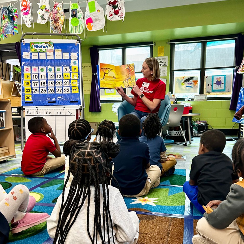 A TUW volunteer reads a picture book to a class of students at an elementary school. 