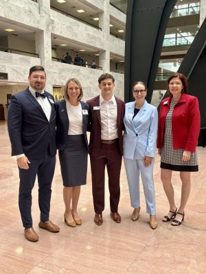 A group of five United Way staff members stand smiling inside of a tall office building in Washington, D.C.