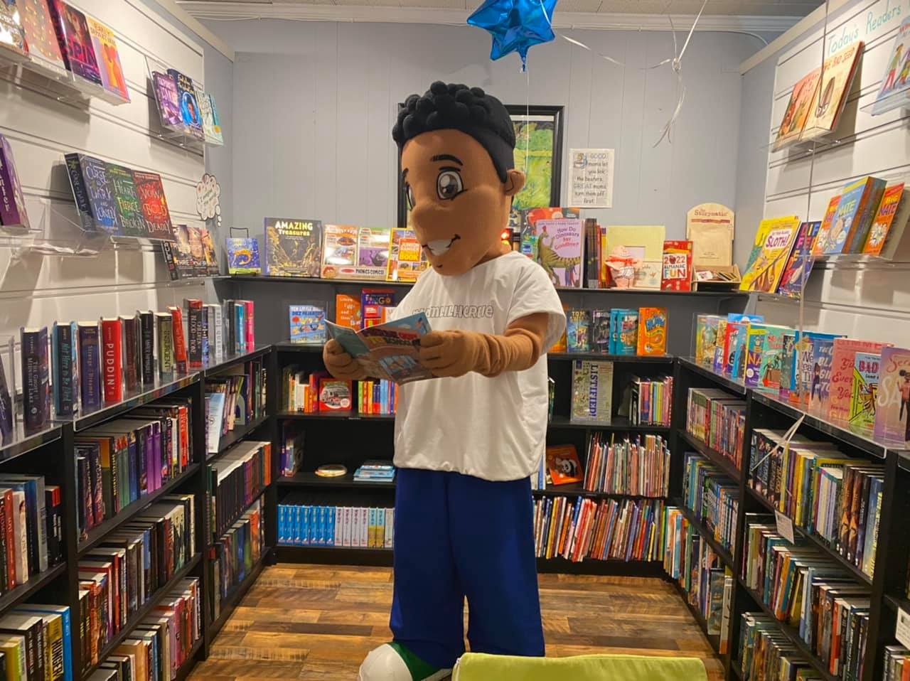 Photo of the Lil Herbie mascot in a bookstore reading a book