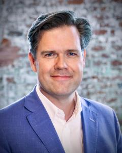 Headshot photo of Peter LaMotte, where a blue jacket and white button up shirt.