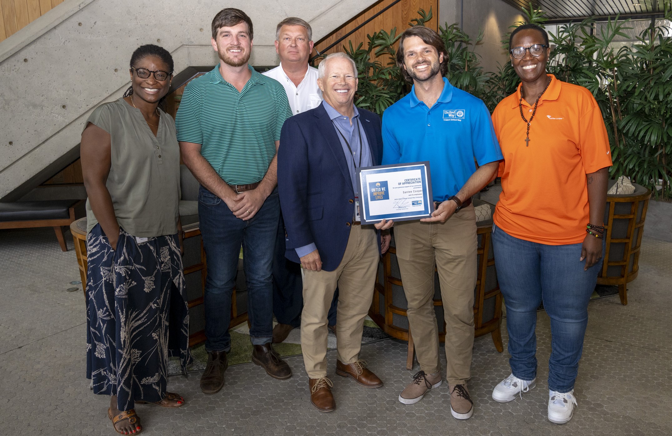 A smiling group of Trident United Way Board Members, employees and Corporate Partners are smiling in a photo holding a certificate.