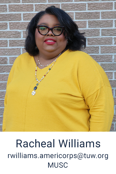 Racheal Williams is standing in front of a brick background, she has shoulder length hair, wears glasses, red lipstick and a yellow sweater