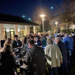 people gathering around the oyster table shucking oysters at night at an event venue. people are socializing in the background