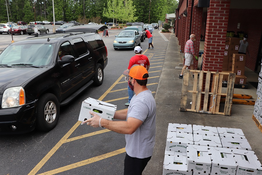 volunteer handing out box of produce to car driving up