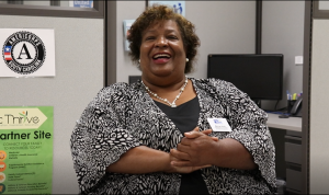 A photo of Melrose Smith smiling at her desk.