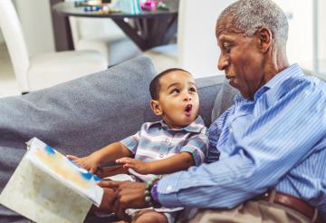 A man reads to a child on the couch.