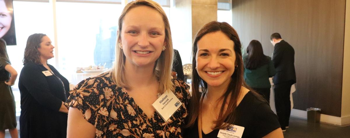 Two young professional women standing and smiling at the camera