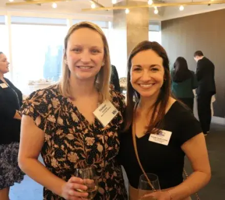 Two young professional women standing and smiling at the camera