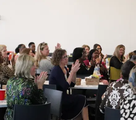 A group of women seated at tables together, applauding