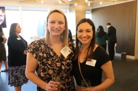 Two young professional women standing and smiling at the camera