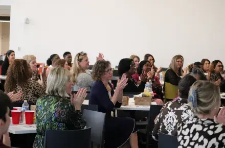 A group of women seated at tables together, applauding