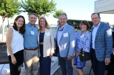 Six members of the Tocqueville Society standing outside together, posing for a photo and smiling