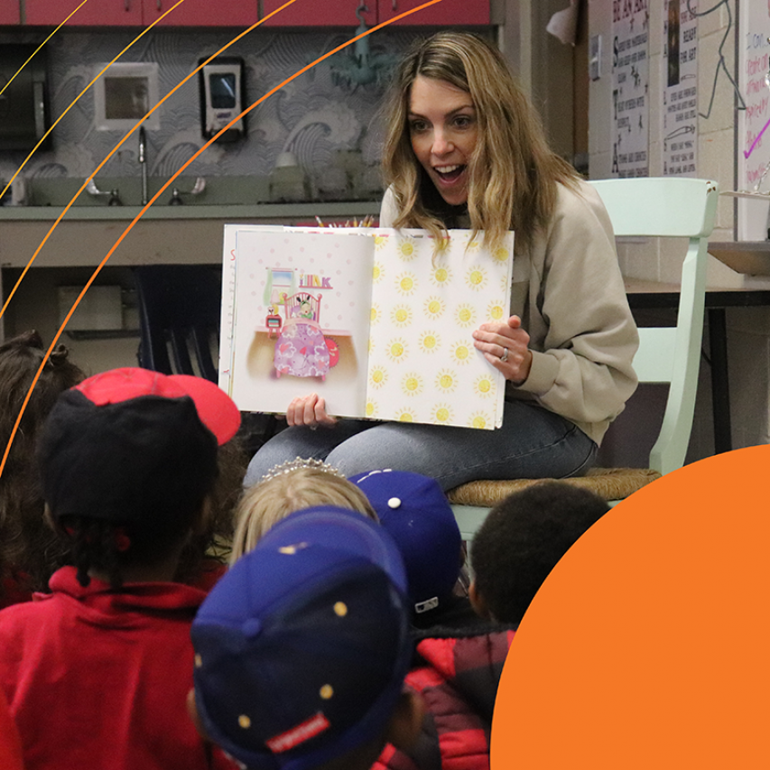 Woman holding a picture book in front of children.