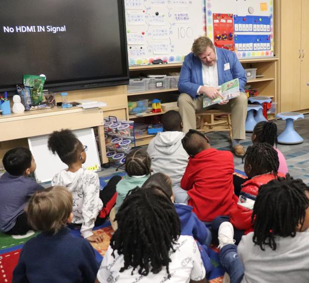 A volunteer reads to students in a classroom