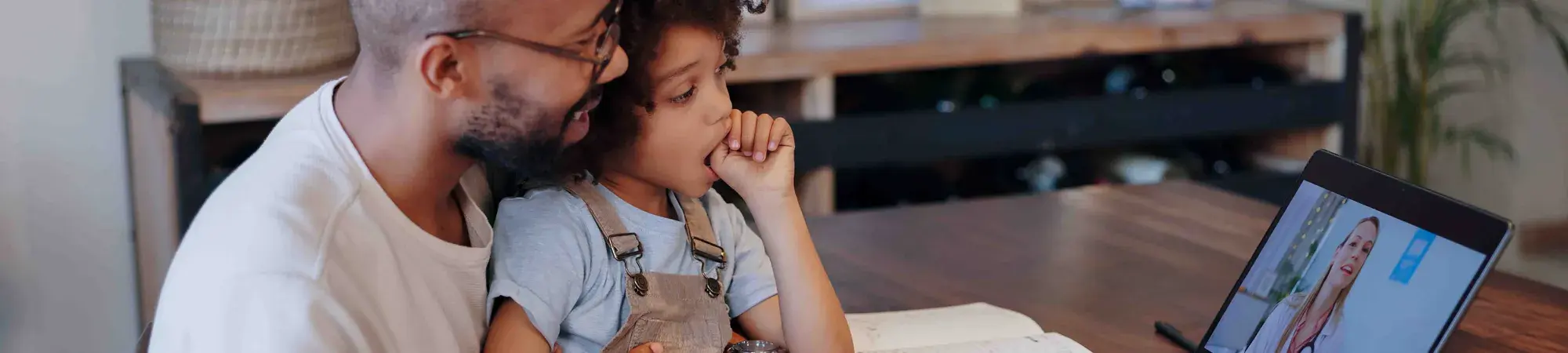 A father and his child talk with a doctor through the computer