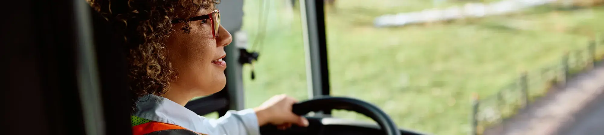 Woman driving a bus, looking hopeful out window