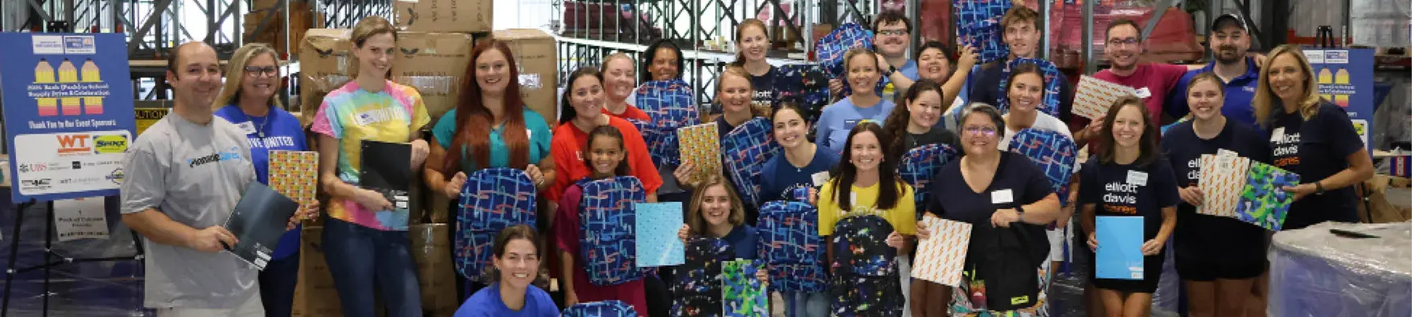 Group of volunteers holds school supplies during packing event