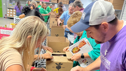 A group of individuals packing boxes assembly line style at foodshare berkeley county