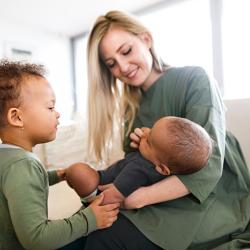 Woman holding baby and toddler looking on