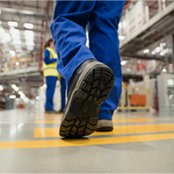 close-up on a person wearing a pair of boots and walking in a warehouse setting